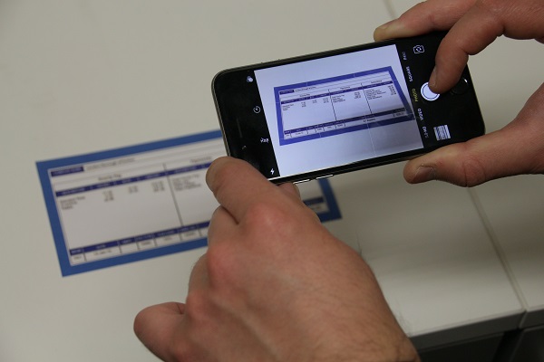 Image showing a customer photographing a document using his smartphone