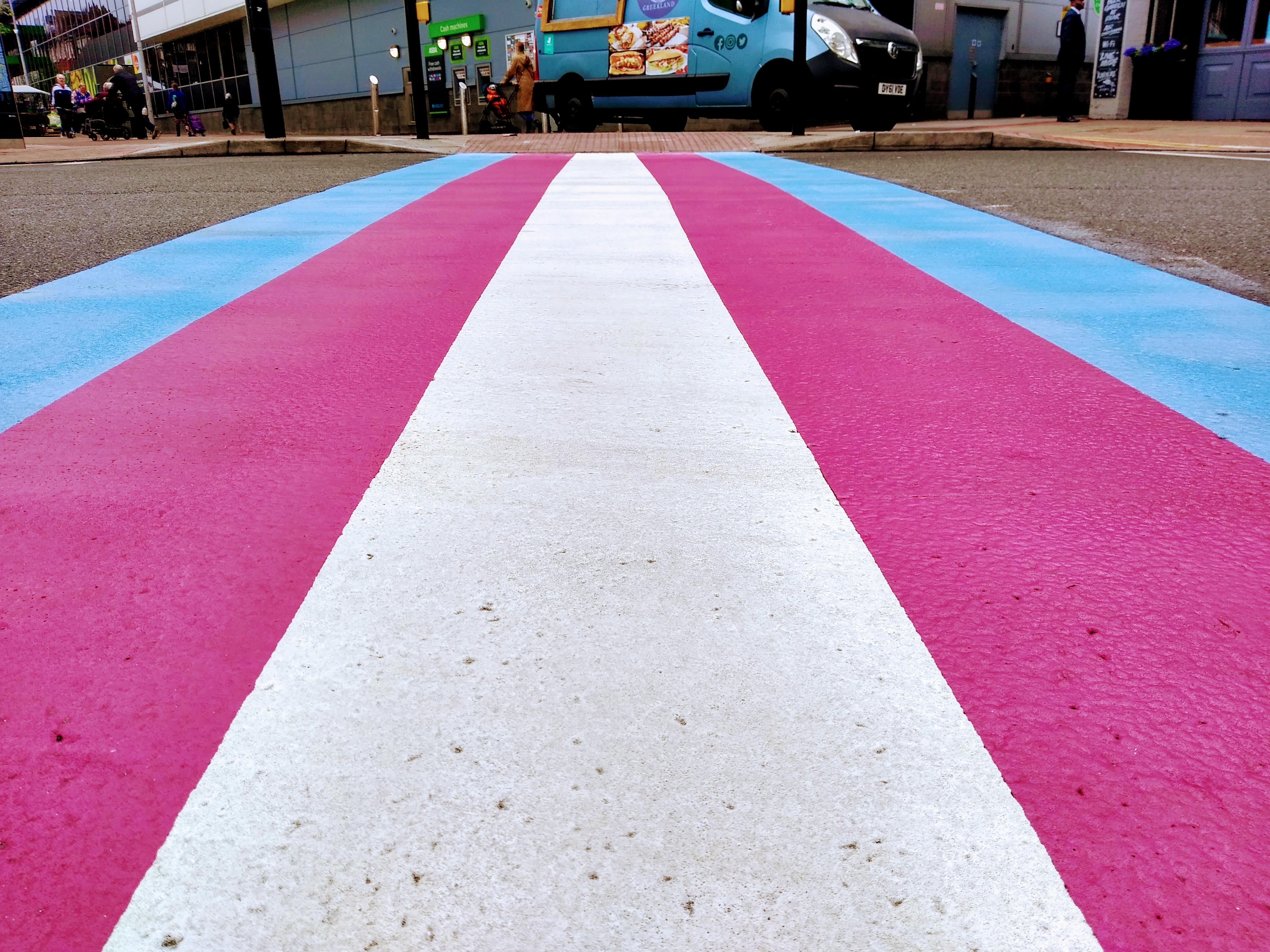 Pedestrian road crossing painted in blue, pink and white stripes - the colours of the transgender flag