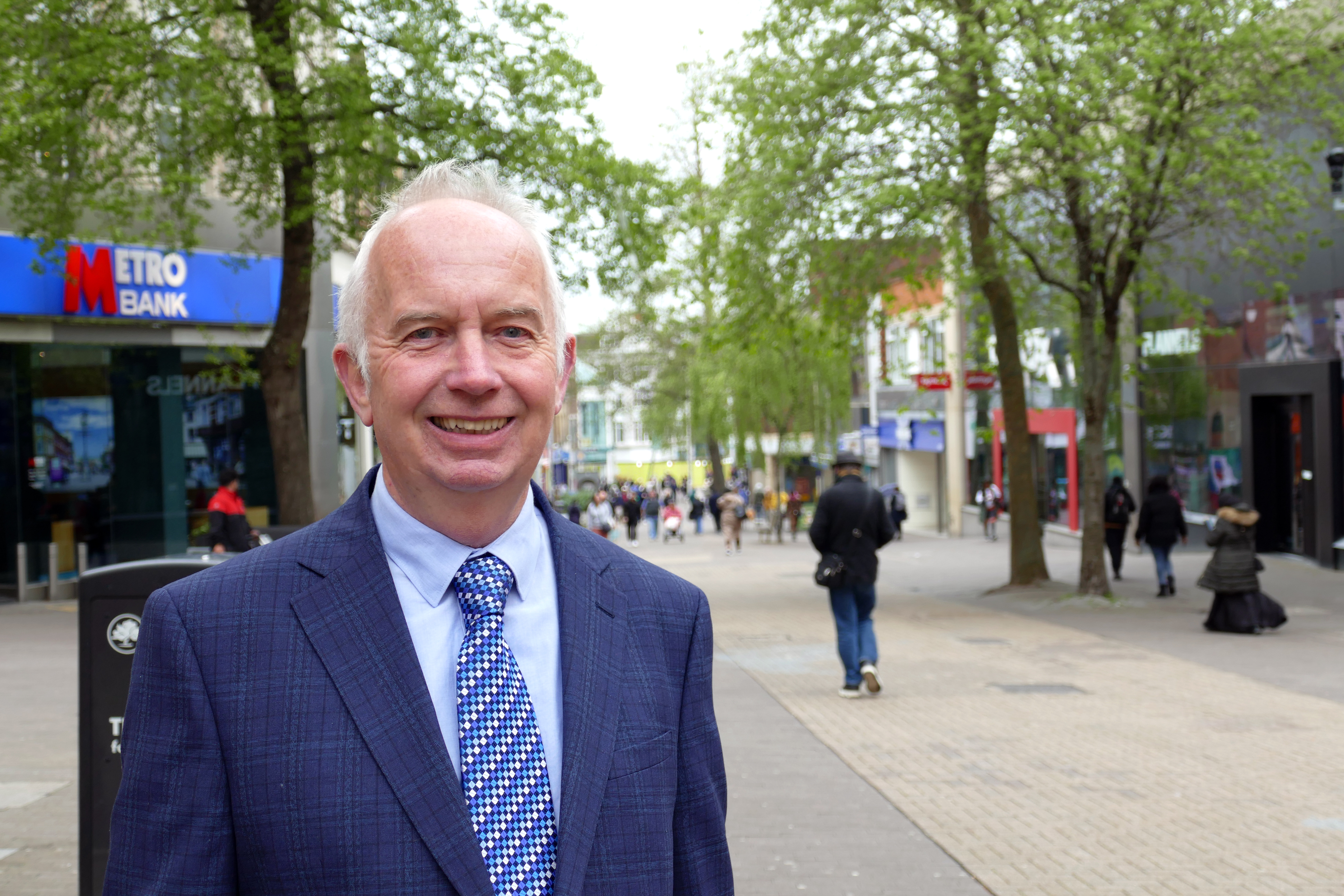 Leader of the Council, Councillor Barry Lewis wearing a blue suit, standing in Sutton High Street.