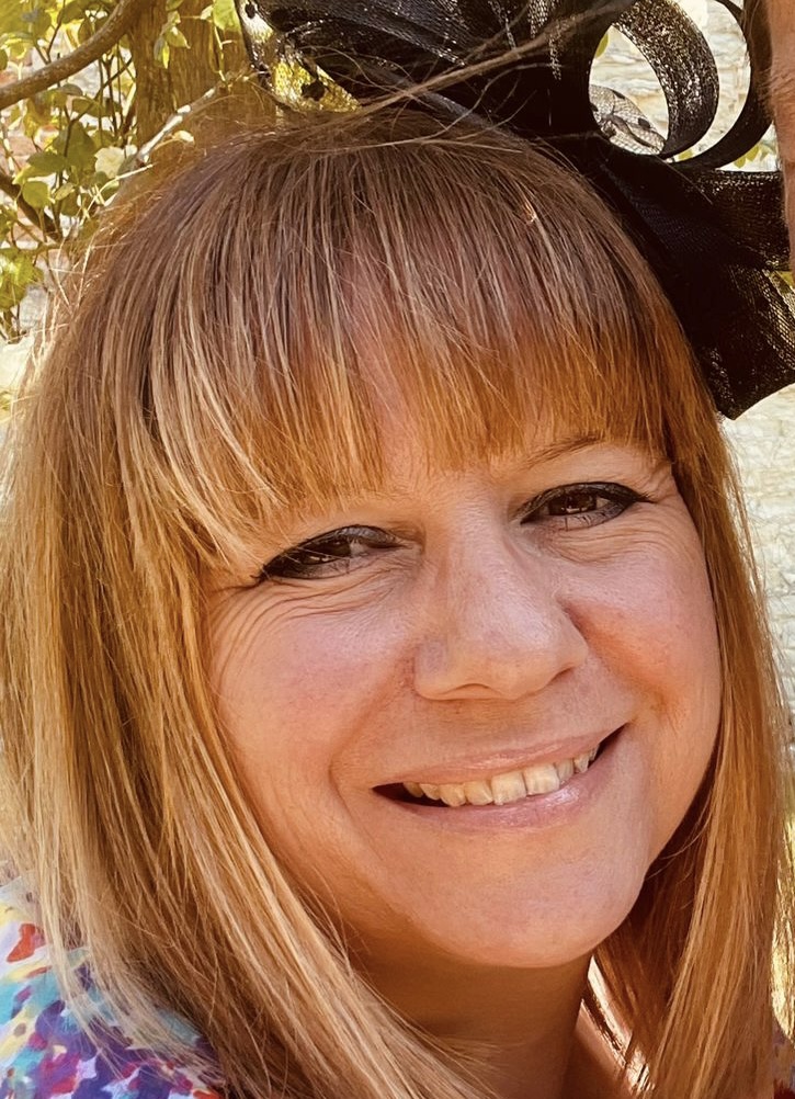 Image is a photograph of a smiling woman's face, with light blond straight hair