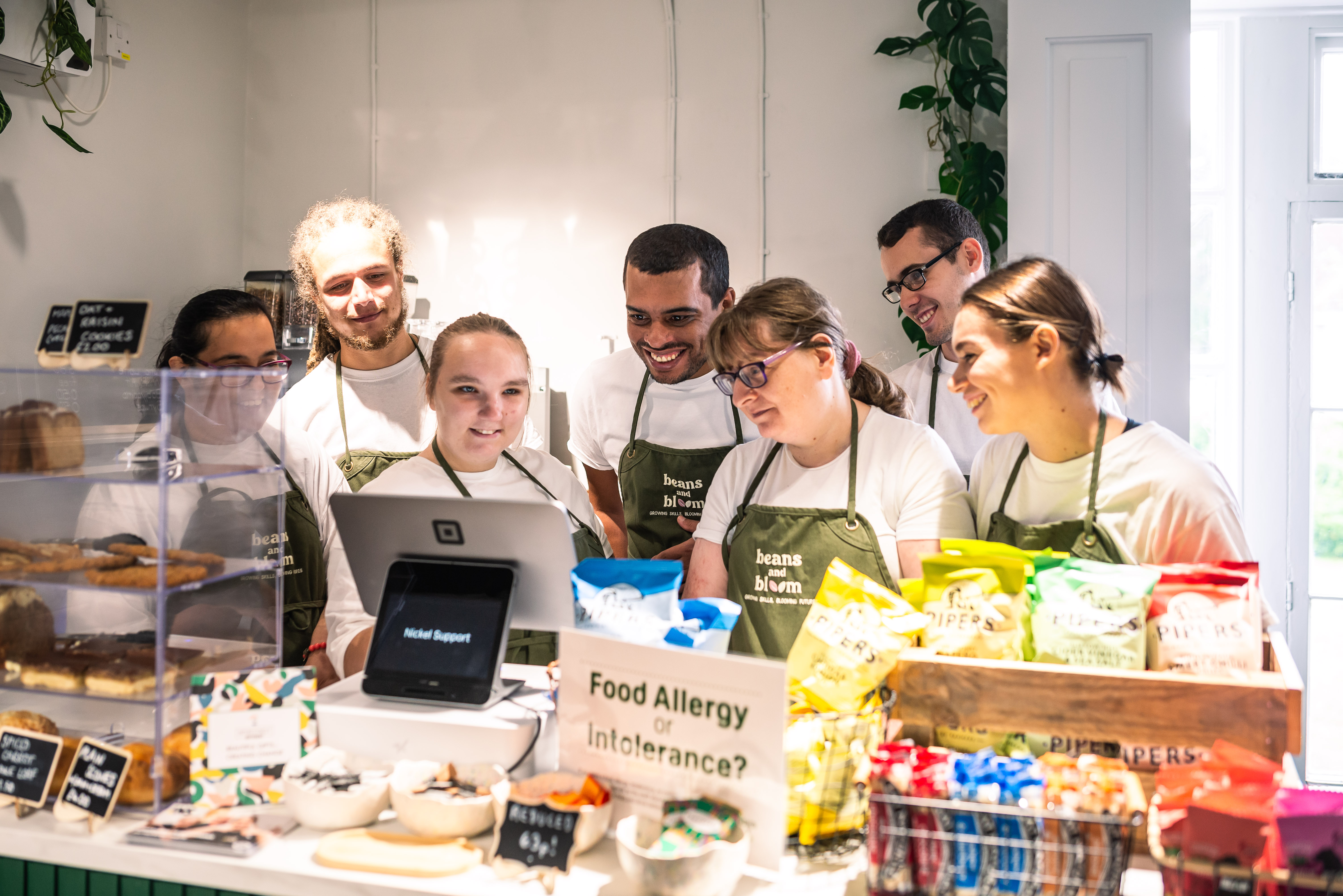 Image shows a group of adults in a coffee shop standing behind the counter. 