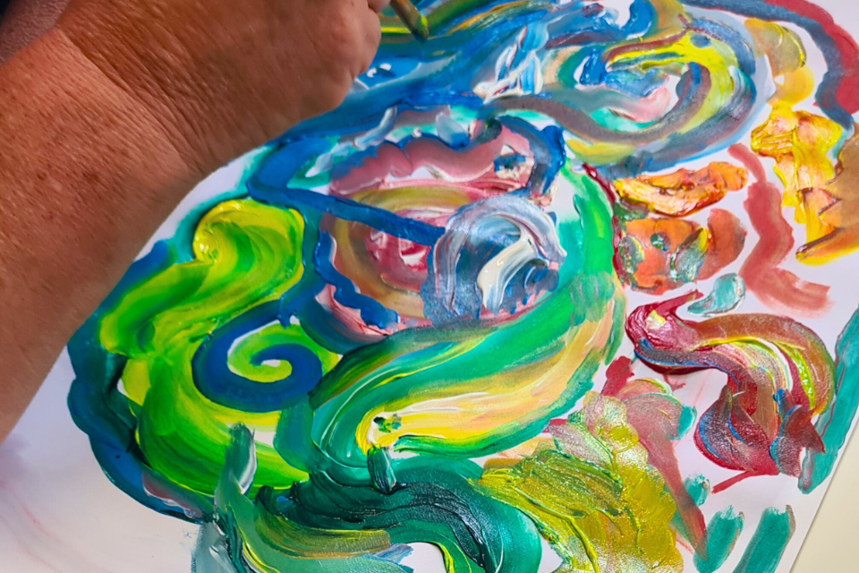 A painting made a several curved paint strokes in green, blue, yellow, red and orange